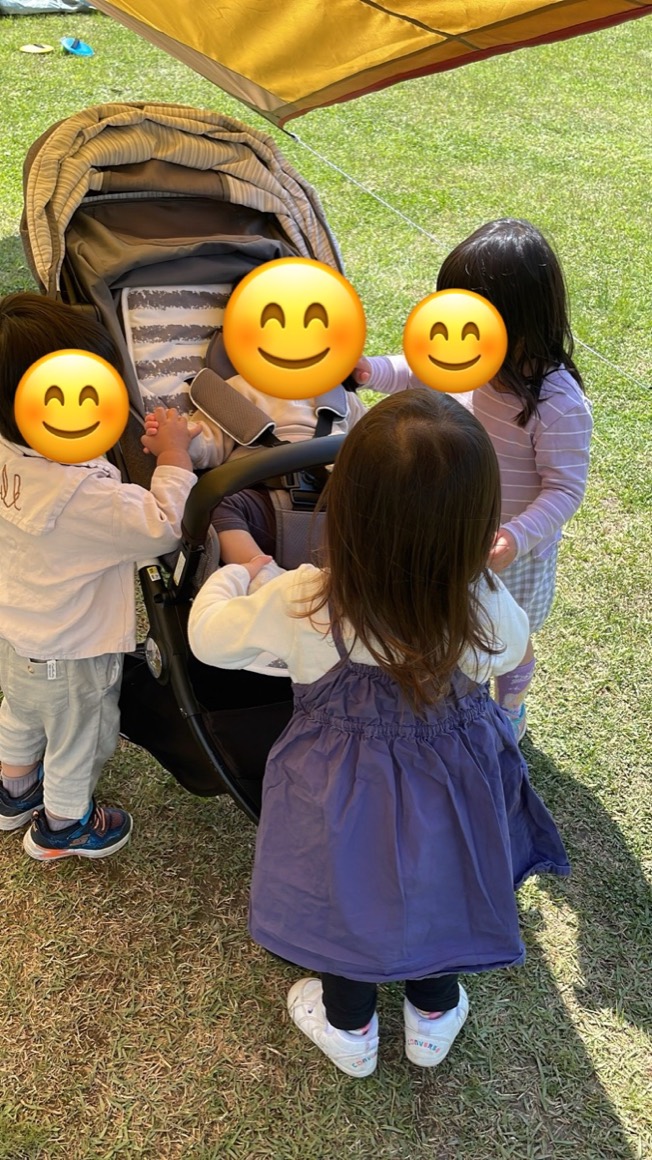 ベビーカーに乗った赤ちゃんを、子どもたちがのぞきこんでいるところ