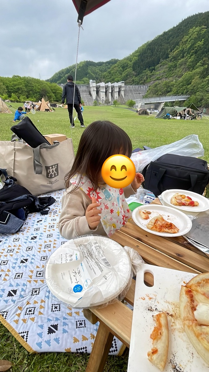 キャンプ場のテーブルでピザを食べる2歳の子ども