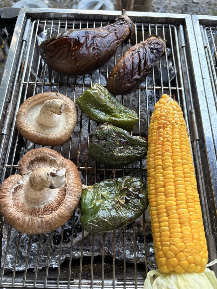 BBQの網の上で丸ごと焼いているなす・椎茸・ピーマン・とうもろこし