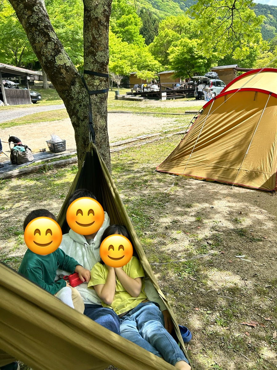 ハンモックに大人1人と子ども2人が並んで座っているところ