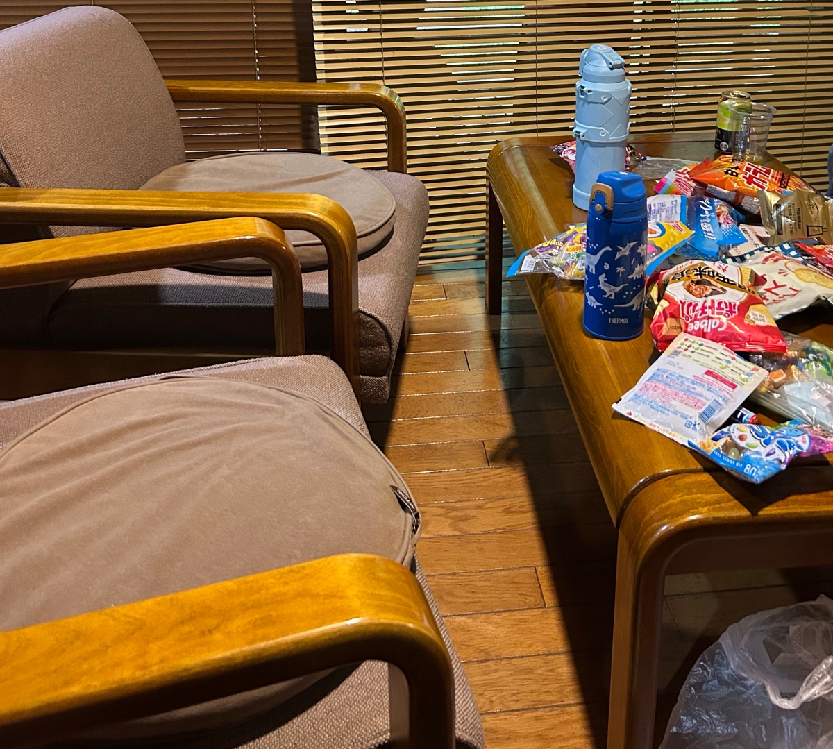 ロッジのリビング。木のひじかけのいすと、お菓子が並んだテーブル