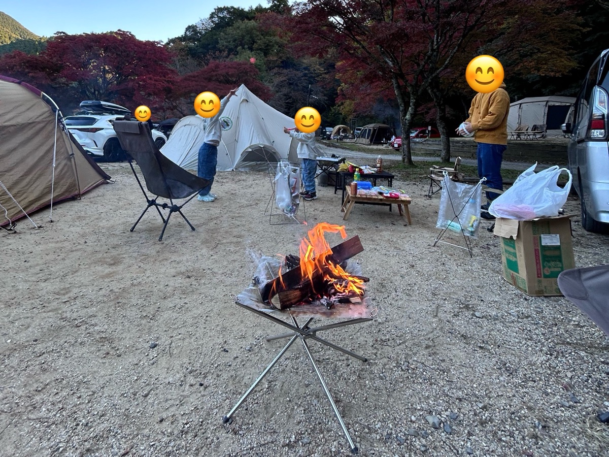 紅葉に囲まれたキャンプ場で、焚き火をしているところ