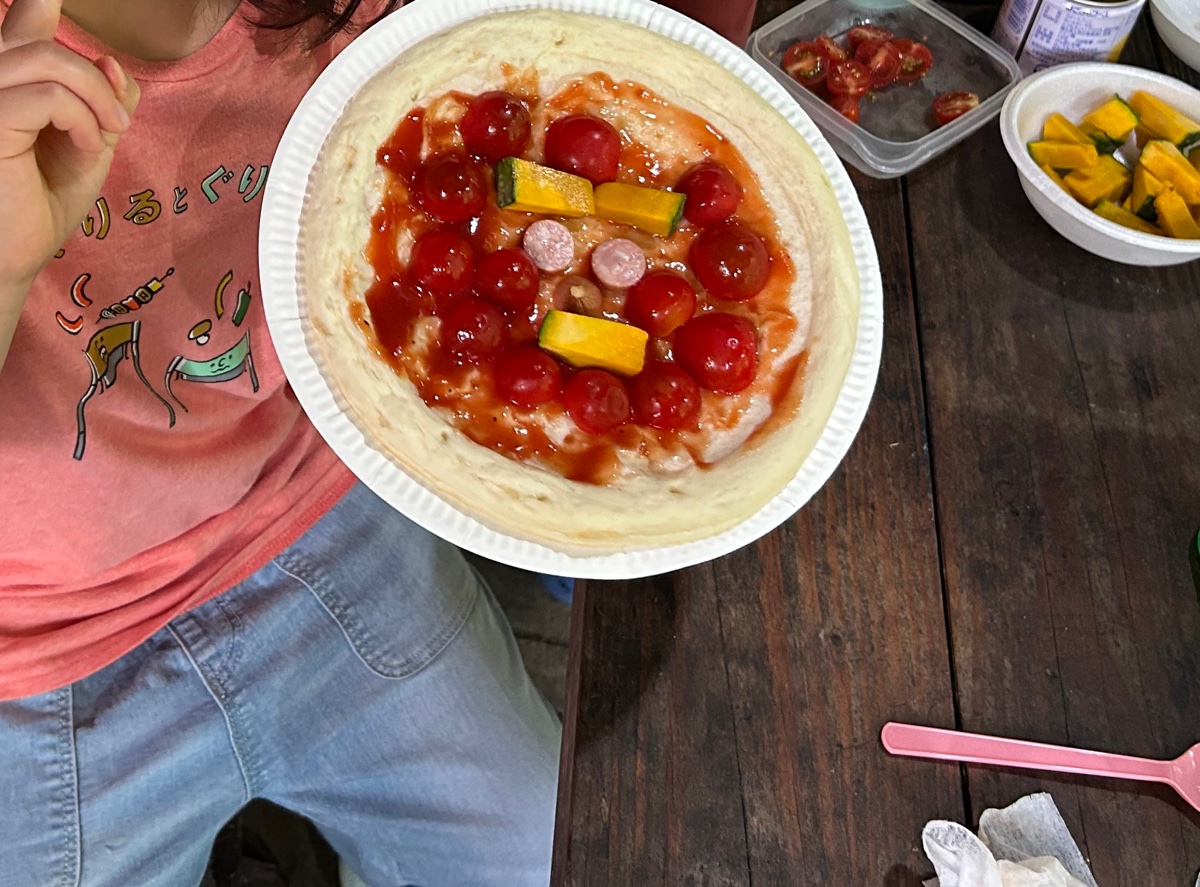 子どもが自分でトッピングしたピザ。ミニトマトとかぼちゃ、ウインナーがのっている