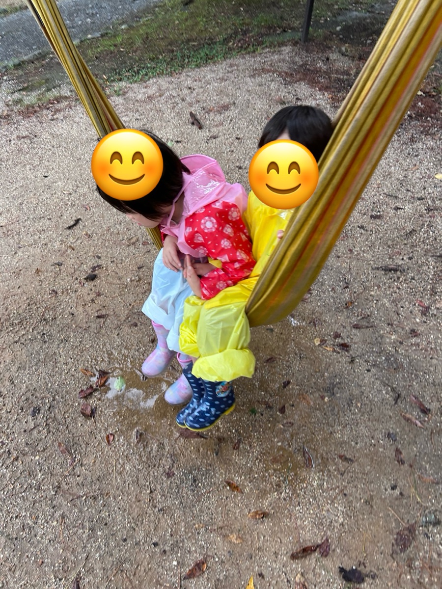 カッパ姿の子ども2人が、ハンモックで遊んでいるところ