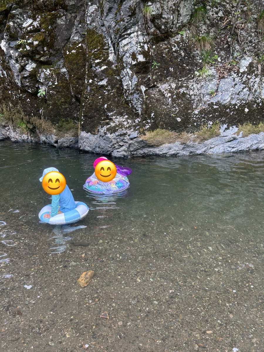 浮き輪に乗って、川の中で遊ぶ子ども2人