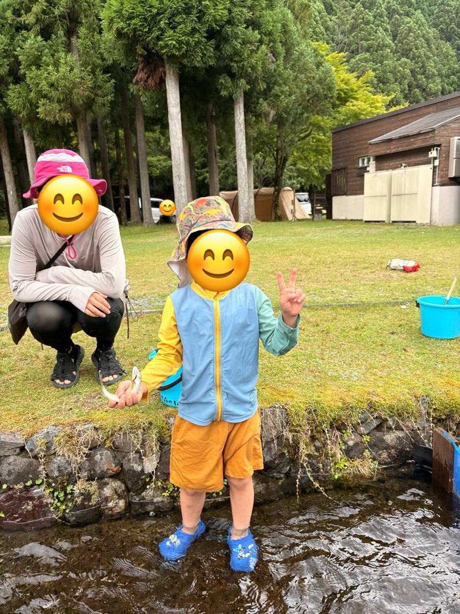 川辺で、ラッシュガードと帽子の子どもと、長袖のラッシュガードにスパッツ姿の親