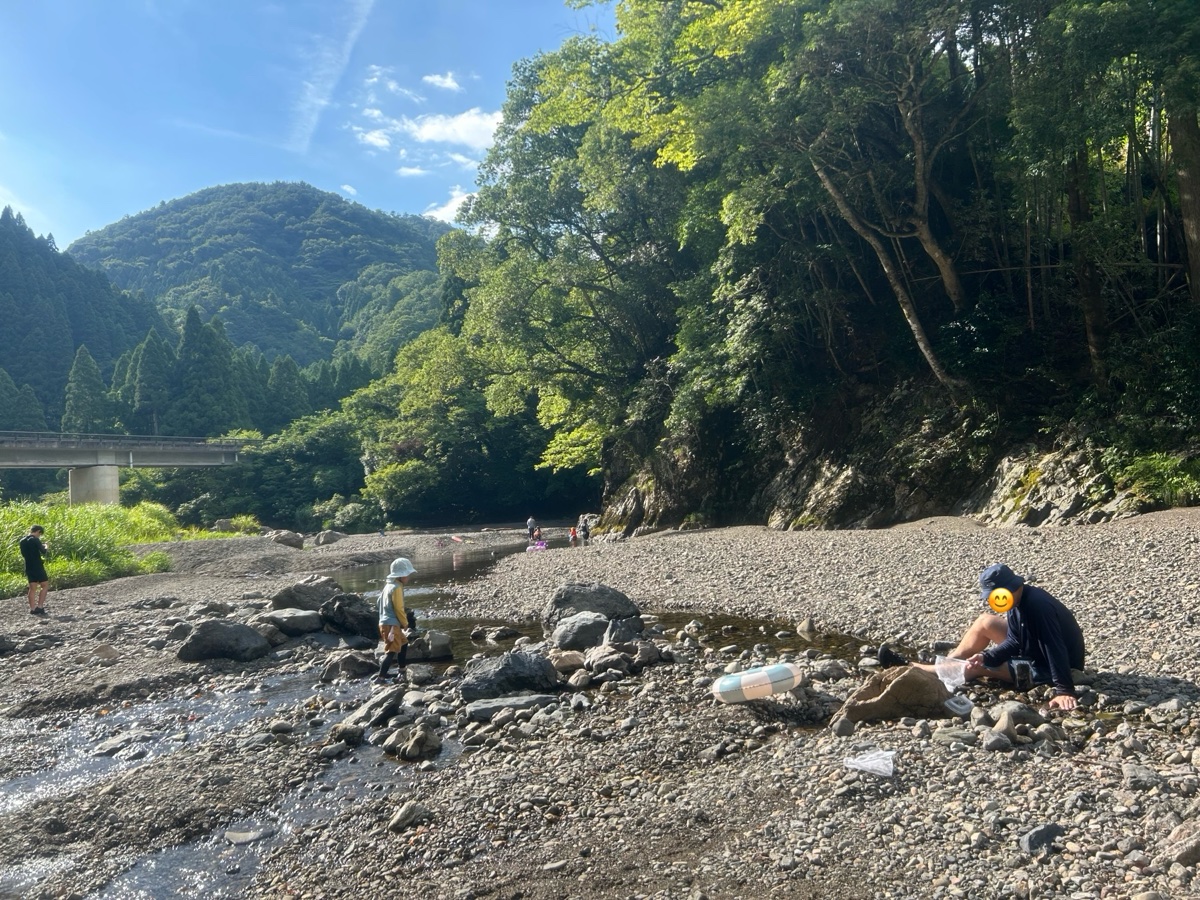 山に囲まれた川原。浅い流れで子どもが遊んでいる