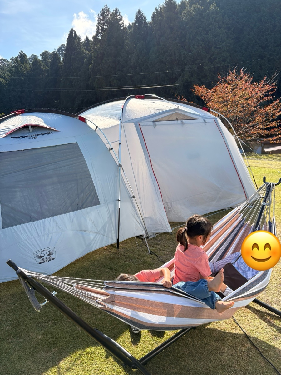テントのすぐ横に置いた自立式ハンモックに、親子で乗っているところ