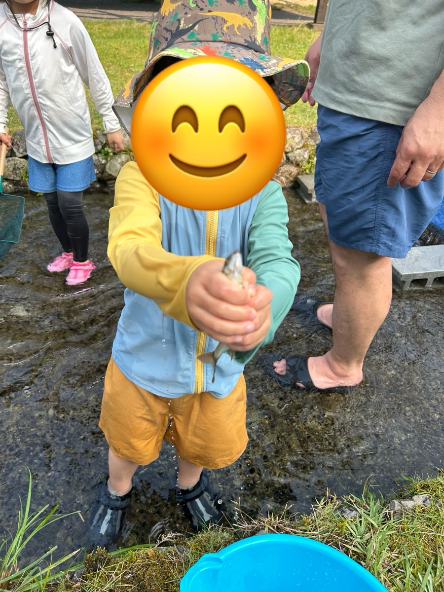 つかんだ魚を手に持って見せる男の子