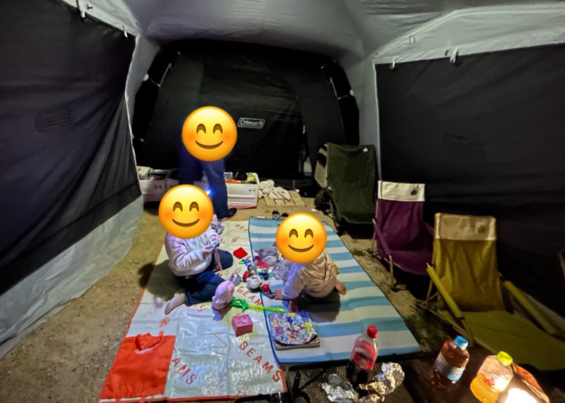 夜、テントの前室にシートを敷いて、おもちゃで遊ぶ子ども2人
